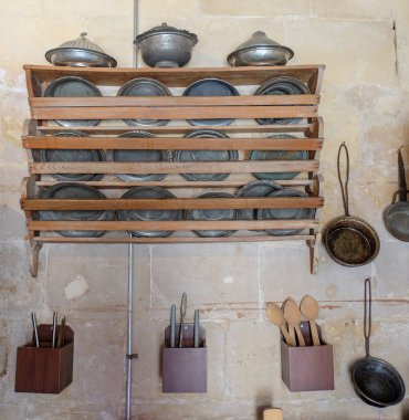 Old copper kitchenware stands on the wooden shelf on the wall, selective focus