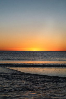 Güneşin günbatımında denizin üzerinde batışı ve sudaki yansıması.