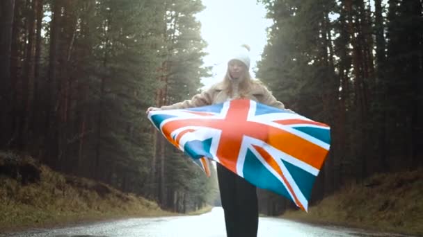 Girl holds the flag of United Kingdom in hands on the road — Stock Video