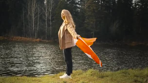 在湖边，一个金发女郎，拿着加拿大国旗 — 图库视频影像