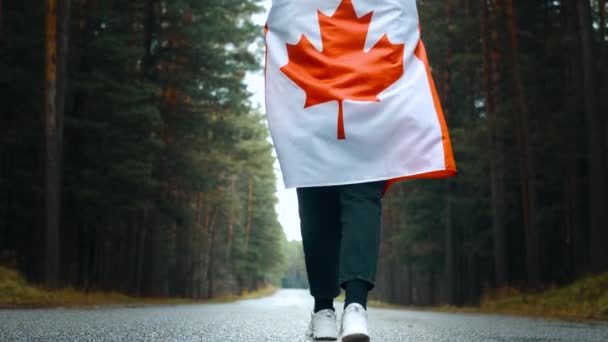Meisje loopt door het bos met de vlag van Canada. Achteraanzicht — Stockvideo