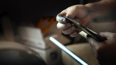 Adam baltanın keskinliğini parmağıyla kontrol ediyor.