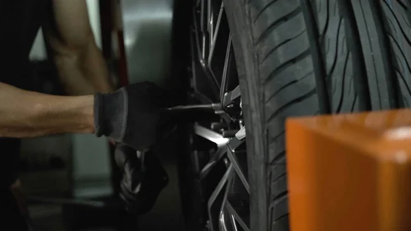 Man tightens the wheel bolts with a wrench
