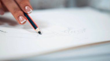 Beyaz tırnaklı kız kağıda bir çizim çiziyor.