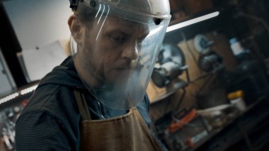 Atölyede koruyucu maskeli bir işçi