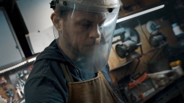 Atölyede koruyucu maskeli bir işçi