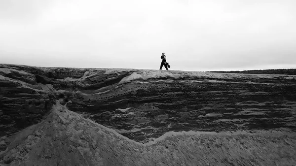 Una chica en overol y una tabla de snowboard está caminando sobre una roca en verano. —  Fotos de Stock