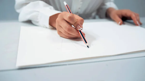 Menina com unhas brancas desenha um esboço no papel — Fotografia de Stock