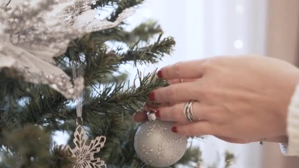 Vrouwelijke handen versieren kerstboom met speelgoed thuis — Stockvideo