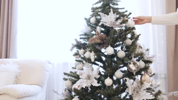 Las manos femeninas decoran el árbol de Navidad con juguetes en casa. Hermosos juguetes de Navidad — Vídeo de stock