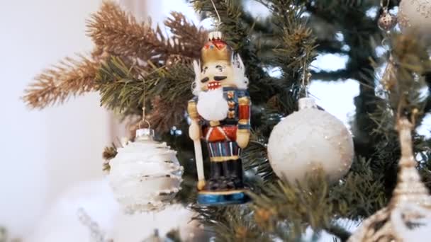 Beautiful light-colored toys hang on the Christmas tree at home. Nutcracker — Stock Video