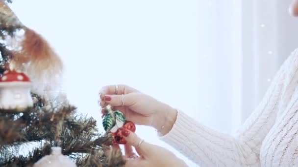 Bella ragazza bruna in un vestito bianco decora l'albero di Natale con giocattoli a casa — Video Stock