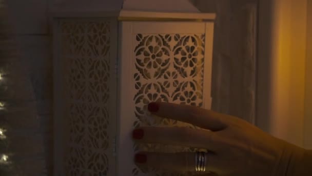 Een meisje in een witte jurk doet 's nachts een kaars in een lamp — Stockvideo