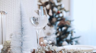 Beyaz elbiseli bir kız bardağa beyaz şarap dolduruyor. Noel güzel konserve masası.