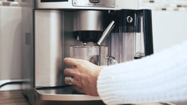 Kadın eli kahve makinesine bir bardak koyar.