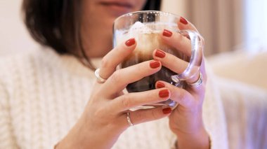 Beyaz elbiseli genç esmer kız kahveyle oturur ve Noel ağacına bakar.