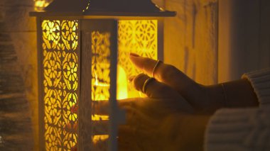 Beyaz elbiseli bir kız gece lambaya mum koyar.