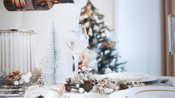 Une fille en robe blanche verse du vin blanc dans un verre. Noël belle table en conserve — Photo