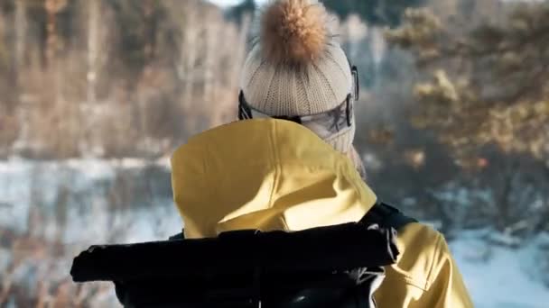 Fille en chapeau blanc et un sac à dos dans la forêt en hiver. Caméra rotative — Video