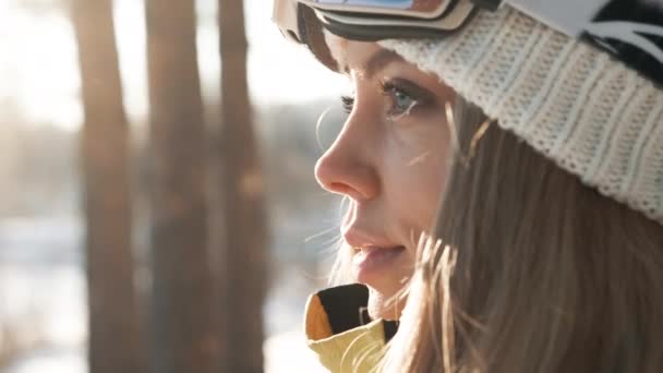 겨울에 숲 속에서 하얀 모자를 쓰고 책가방을 든 소녀. 태양 광선 — 비디오