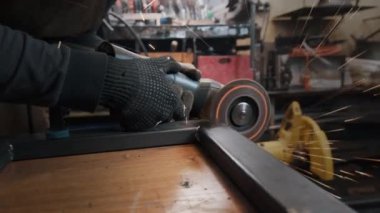 Eldivenli bir adam metali dairesel bir testereyle keser, bir sürü kıvılcım saçar. Çalışma süreci