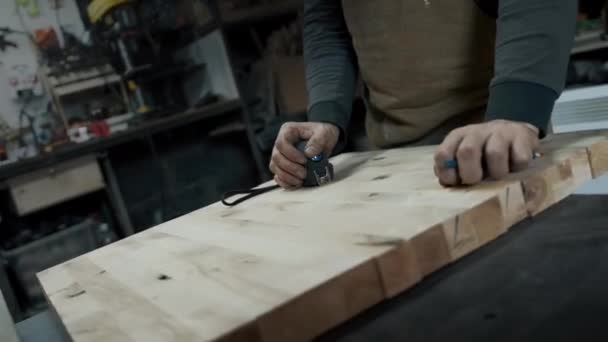 Manos de carpintero en un delantal y un trozo de madera — Vídeos de Stock