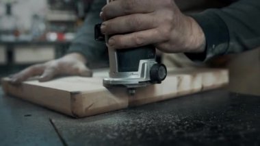 Bir marangoz ahşap bir sandalyenin kenarlarını değirmenliyor..