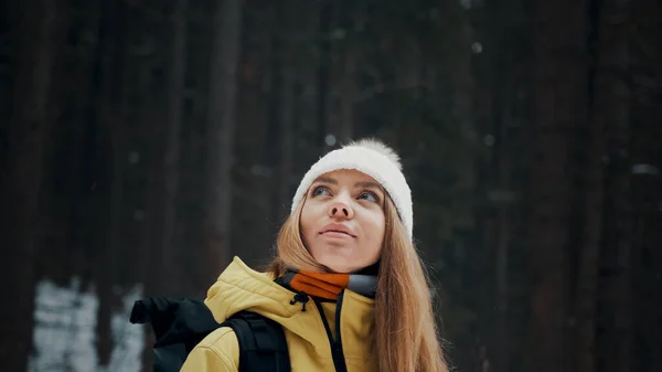 Menina com um chapéu branco na floresta com uma mochila no inverno. Vista lateral. Fechar — Fotografia de Stock