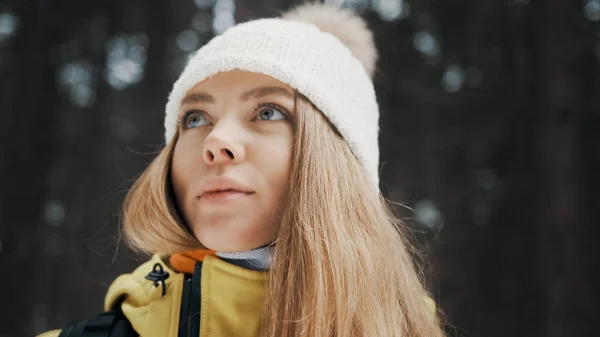 Menina com um chapéu branco na floresta com uma mochila no inverno. Vista lateral. Fechar — Fotografia de Stock