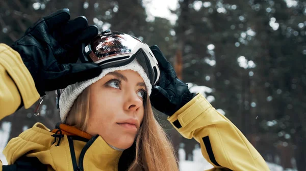 Menina com um chapéu branco e máscara de snowboard na floresta no inverno. Vista lateral. Fechar — Fotografia de Stock
