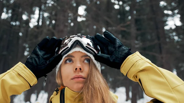 Menina com um chapéu branco e máscara de snowboard na floresta no inverno. Vista lateral. Fechar — Fotografia de Stock