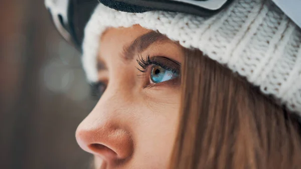 Dívka s bílým kloboukem a snowboardovou maskou v lese v zimě. Boční pohled. Makro oči — Stock fotografie