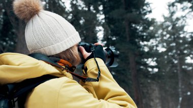 Sırt çantası ve sarı anorak taşıyan bir kız profesyonel bir kamerada manzarayı fotoğraflıyor.
