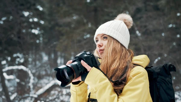 Una ragazza con uno zaino e un anorak giallo fotografa il paesaggio su una macchina fotografica professionale — Foto Stock