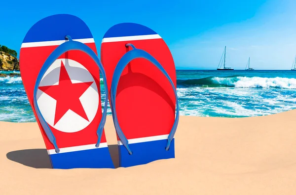 Flip flops with North Korean flag on the beach. North Korea resorts, vacation, tours, travel packages concept. 3D rendering