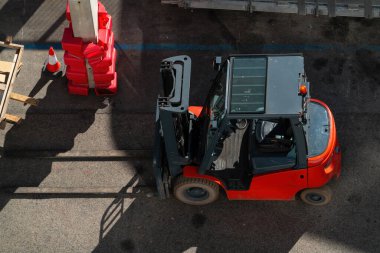 Endüstriyel alanda kırmızı bir forklift var.