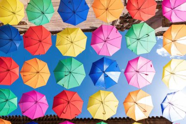 Mavi gökyüzüne karşı asılı renkli şemsiyeler