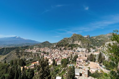 Yeşil tepelerdeki Taormina kasabasının panoramik manzarası. Arka planda Etna Yanardağı, Sicilya, İtalya