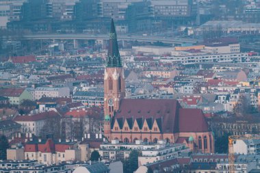 St. Leopoldskirche Donaufeld neo gotik tuğla kilisesi ve yoğun çatıların üzerinde yükselen uzun saat kulesiyle Viyana manzarası. Viyana, Avusturya