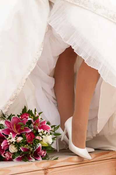 Bride's legs with boquet — Stock Photo, Image