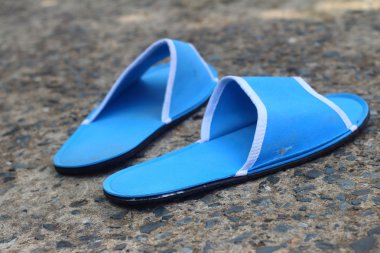 Çimento bir arka plan üzerinde mavi terlik.