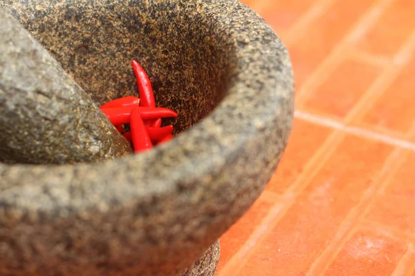 Chiles rojos en un mortero sobre un fondo naranja . — Foto de Stock