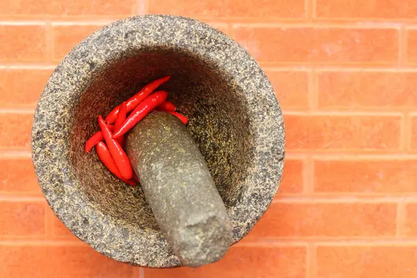 Red Chilies in a mortar on an orange background. — Stock Photo, Image