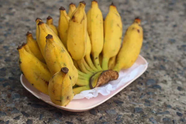 Bananas place on a pink plate on cement — Stock Photo, Image