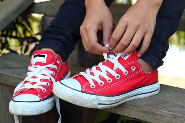 Mujer sentada encajes sus zapatos en el parque — Foto de Stock