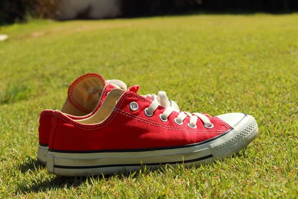Cipő piros, a zöld fű a parkban. — Stock Fotó