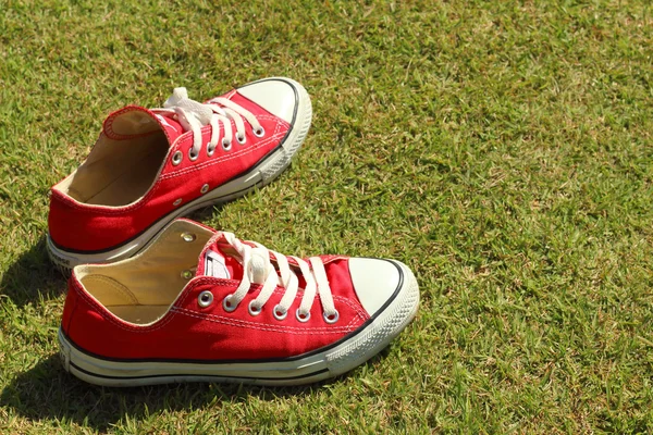 Parkta yeşil çimenlerin üzerinde kırmızı ayakkabılar.