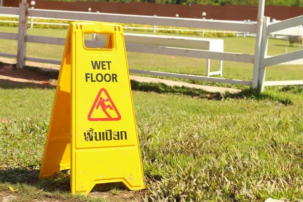 Żółty znak ostrzegawczy na mokrej podłodze w parku — Zdjęcie stockowe