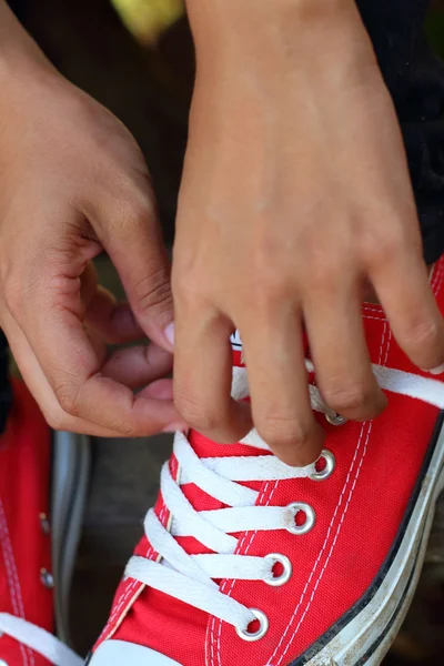 Woman sitting laces her shoes at the park — Stock Photo, Image