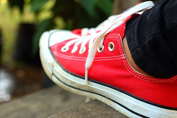 Sapatos vermelhos em um fundo marrom no parque . — Fotografia de Stock